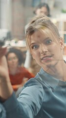Poster - Portrait of White Female Specialist Writing on Glass Board and Brainstorming with Team in a Stylish Meeting Room in Creative Office. Team of Multi-Ethnic Professionals Building Marketing Strategy