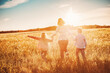 © candy1812 - Mother with her children running on the field on the summer sunset.