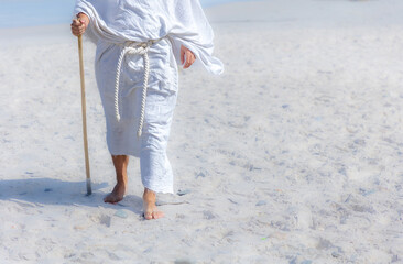 Wall Mural - close up of a Biblical man in a white robe and staff walking in desert