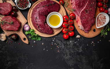 Canvas Print - Assortment of raw cuts of raw beef meat steaks with spices on a dark background. Long banner format. top view