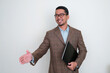 © KrishnaTedjo - Asian businessman wearing brown suit holding a laptop want to do handshake with happy expression