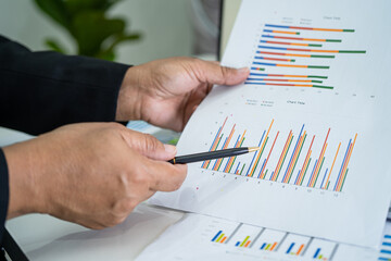 Asian accountant working and analyzing financial reports project accounting with chart graph and calculator in modern office, finance and business concept.