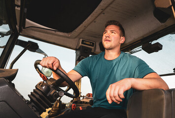 Poster - Junger Landwirt sitzt auf einen Traktor.