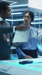 Leinwandbilder - Vertical Screen: Two Multiethnic Employees Work in Modern Innovative Research Facility on a Project. Engineer with a Laptop Explaining How the Prototype Works to an Industrial Specialist.