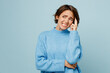 Young mistaken sad unhappy caucasian woman wear knitted sweater look aside on workspace area prop up chin isolated on plain pastel light blue cyan background studio portrait. People lifestyle concept.