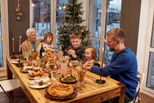 Big Family Sitting At Table Together In Cozy Atmosphere Waiting For Christmas Dinner