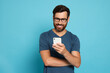 © New Africa - Happy man looking at smartphone on light blue background