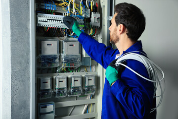 Sticker - Electrician with wires switching off circuit breakers in fuse box indoors