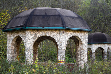 Park gazebos with arched windows made of raw natural stone