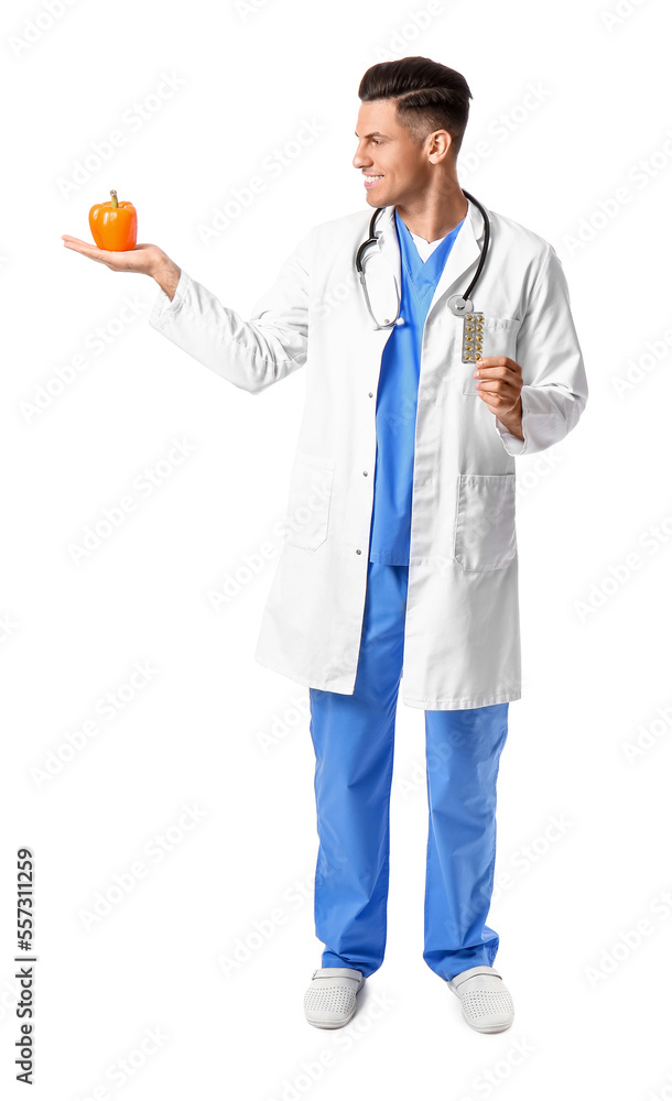 Male doctor with vitamins and bell pepper on white background