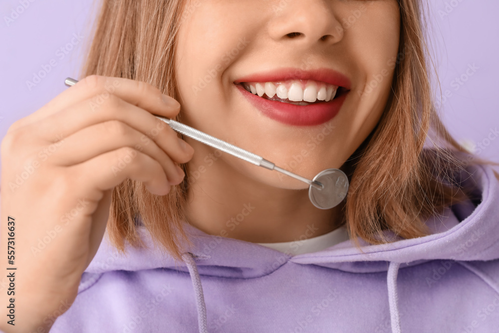 Young woman with dental tool smiling on lilac background, closeup