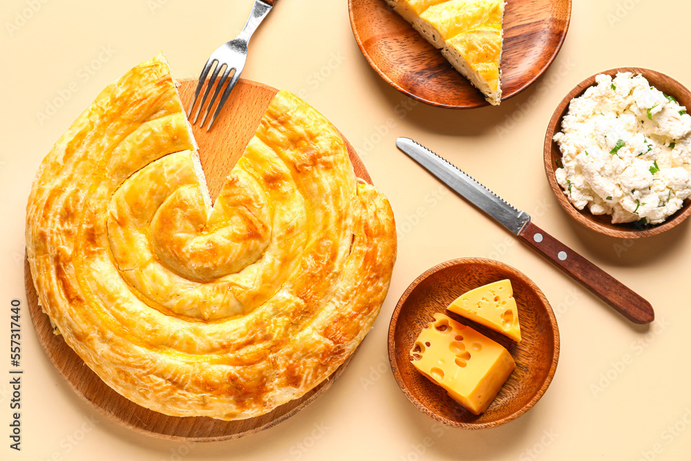 Board and plate with delicious cheese pie on beige background