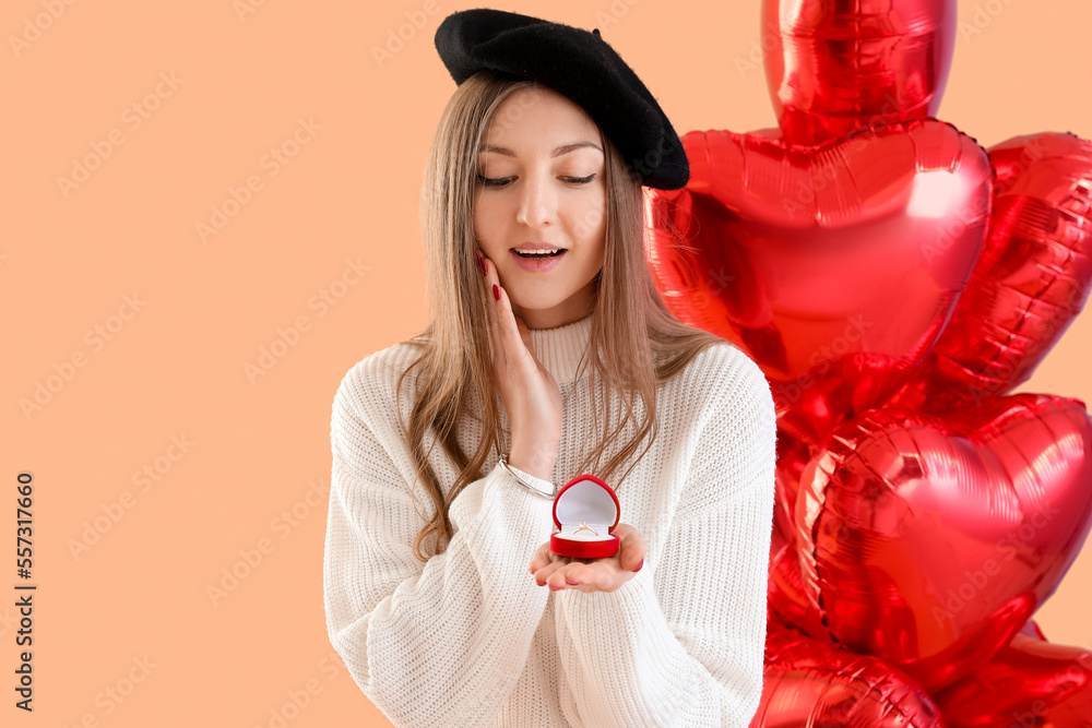 Young woman with engagement ring and balloons on beige background. Valentine's Day celebration