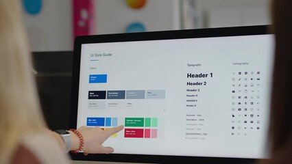 corporate graphic designer coworkers look at a font and color branding sheet on a computer screen po
