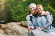 © Jesse B/peopleimages.com - Nature, hiking and portrait of a senior couple relaxing while walking in a forest for exercise. Love, happy and elderly people with a smile sitting to rest while trekking together in the woods.