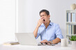 © Paitoon - Businessman yawning in front of the laptop at office desk.