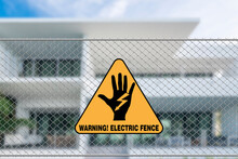 An Electric Fence Warning Sign In Front Of A House. A Caution Signage To Trespassers.