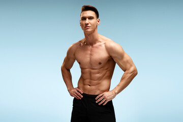 Poster - Young man bodybuilder showing his muscular body against blue background