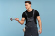 © speed300 - Focused young mechanic holding a wrench isolated on blue background