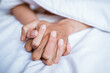 © Odua Images - close up of a couple's hands while making love on the bed