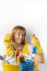 Happy young caucasian woman in a uniform wearing yellow rubber gloves and holding bucket full of cleaning supplies. Cleaning company service advertisement. Free space for text. House cleaning concept