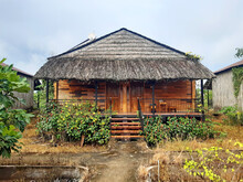Wooden Bungalow With A Thatched Roof In A Rustic Mekong Setting. Rustic Oriental House Among Tropical Vegetation. Thatched Roof. Architecture And Details Of Asian Huts.