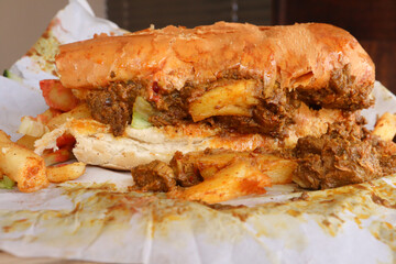 Masala steak Gatsby. Traditional South African fast food. Chips, steak and salad on a large roll