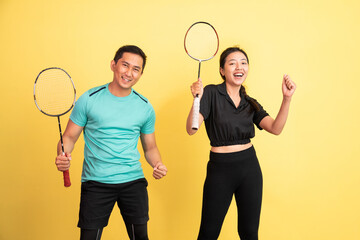 excited women and men standing holding rackets on yellow background