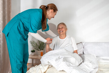 Nurse helping an elderly woman at her home. Solicitous professional medical female staff caring in a geriatric institution with a senior patient. Lifestyle