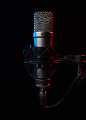 professional large diaphragm microphone for podcast on black background backlighted with red colour