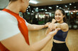 © Odua Images - young asian woman doing punching moves guided by male instructor