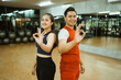 © Odua Images - girl and guy in sportswear standing back to back with okay hand gesture to camera