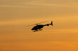Tourist helicopter flying in the sky at sunset.