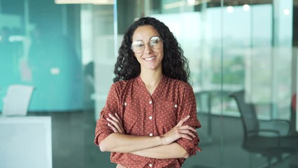 portrait young woman creative employee developer female engineer university teacher or student look at camera smiling in modern office Curly brunette in casual business woman worker in glasses indoor