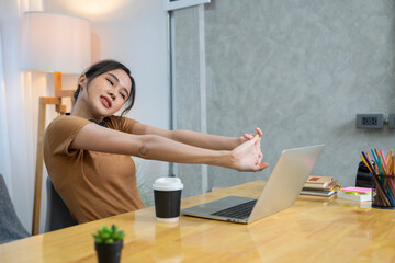 Female college student in headphones typing homework report on laptop until feeling pain in shoulders and stretching arms. office syndrome concept