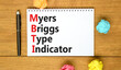 MBTI Myers Briggs type indicator symbol. Concept words MBTI Myers Briggs type indicator on white note on beautiful wooden background. Psychological MBTI Myers Briggs type indicator concept. Copy space