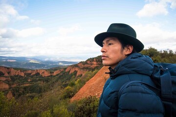 Long-haired man in hat walking in remote nature