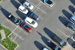 Aerial view of many colorful cars parked on parking lot with lines and markings for parking places and directions