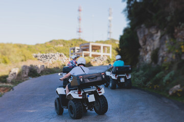 Wall Mural - Group of riders riding ATV vehicle crossing mountain serpentine road track, process of driving rental vehicle, all terrain quad bike vehicle, during off-road tour, Greece, Ionian sea islands