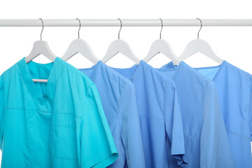 Wall Mural - Turquoise and light blue medical uniforms on rack against white background