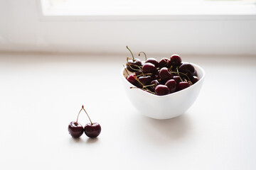 Wall Mural - Fresh ripe cherries on a plate in the shape of a heart on a white background. Vitamins and healthy nutrition