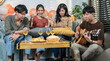 © supAVADEE BUTRADEE - Group of asian friends girls and boys having a party drinking wine and boys playing guitar and singing together having fun at the party.