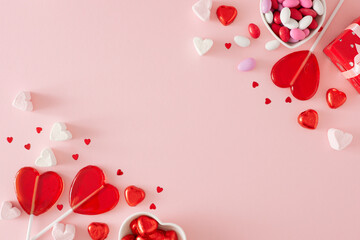 St Valentine's Day concept. Creative composition made of gift boxes and heart shaped saucers with chocolate candies, lollipops and marshmallow on pastel pink background. Flat lay with copy space.