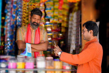 Indian rural customer using smartphone for digital payment at groceries shop