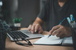 © khunkornStudio - man hands with pen writing on notebook in the office.learning, education and work.writes goals, plans, make to do and wish list on desk.