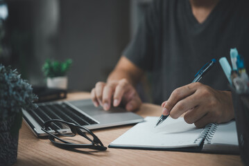man hands with pen writing on notebook in the office.learning, education and work.writes goals, plans, make to do and wish list on desk.