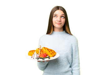 Sticker - Teenager girl holding waffles over isolated chroma key background and looking up