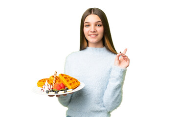 Sticker - Teenager girl holding waffles over isolated chroma key background showing and lifting a finger in sign of the best