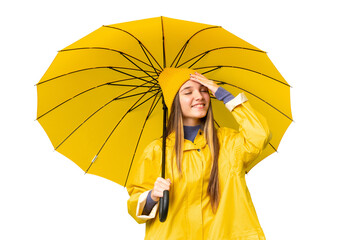 Wall Mural - Teenager girl with rainproof coat and umbrella over isolated chroma key background smiling a lot