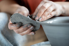 Close Up Of Female Hands Shaping Clay With Sculpting Tool Using Trimming Knife, Ceramist Holding Metal Rib While Making Pottery On Wheel, Potter Using Steel Scraper In Work. Handmade Stoneware Concept